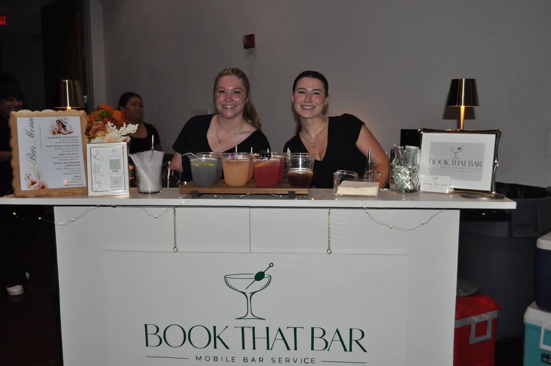 Two smiling bartenders behind the Book That Bar mobile bar