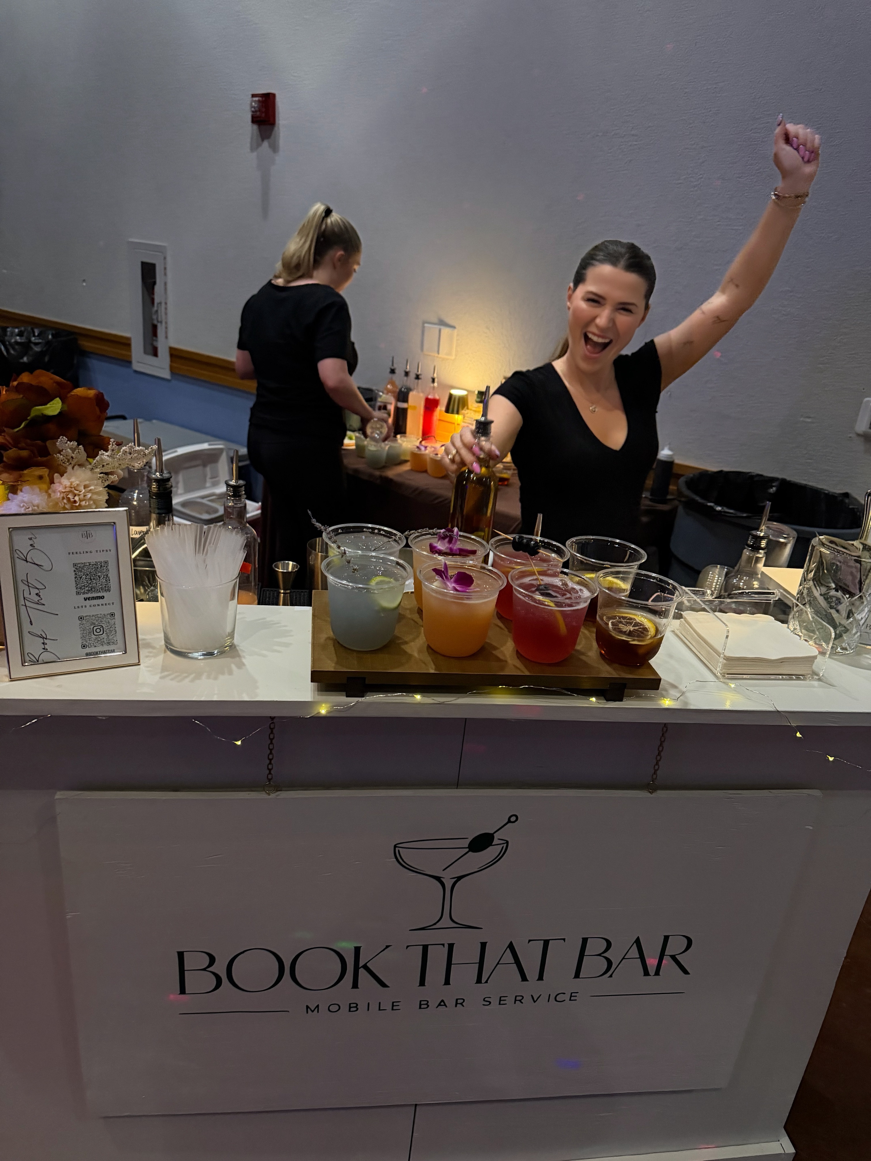 Bartender celebrating behind a display of colorful cocktails