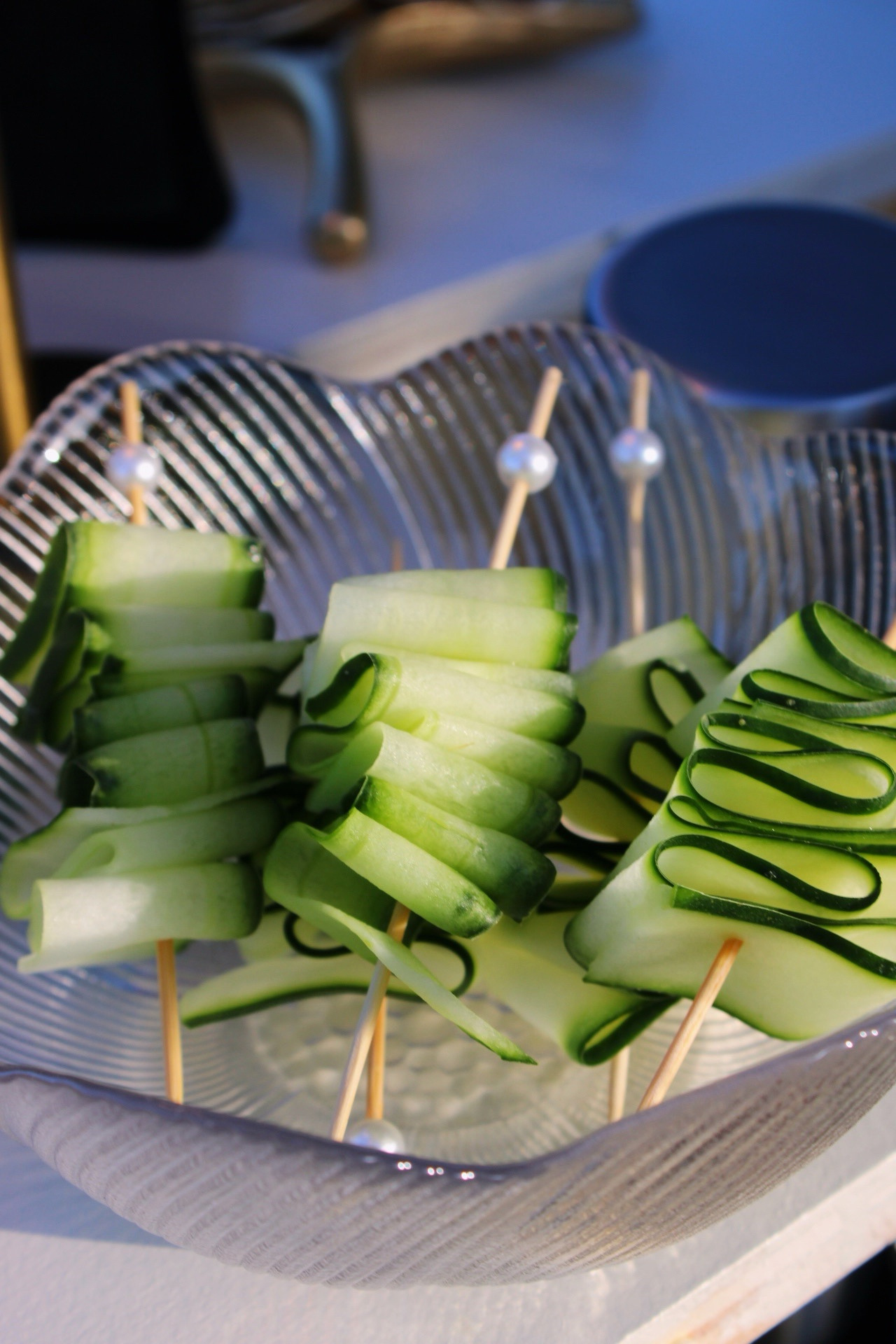 Hand-folded cucumber ribbon garnishes arranged on cocktail picks