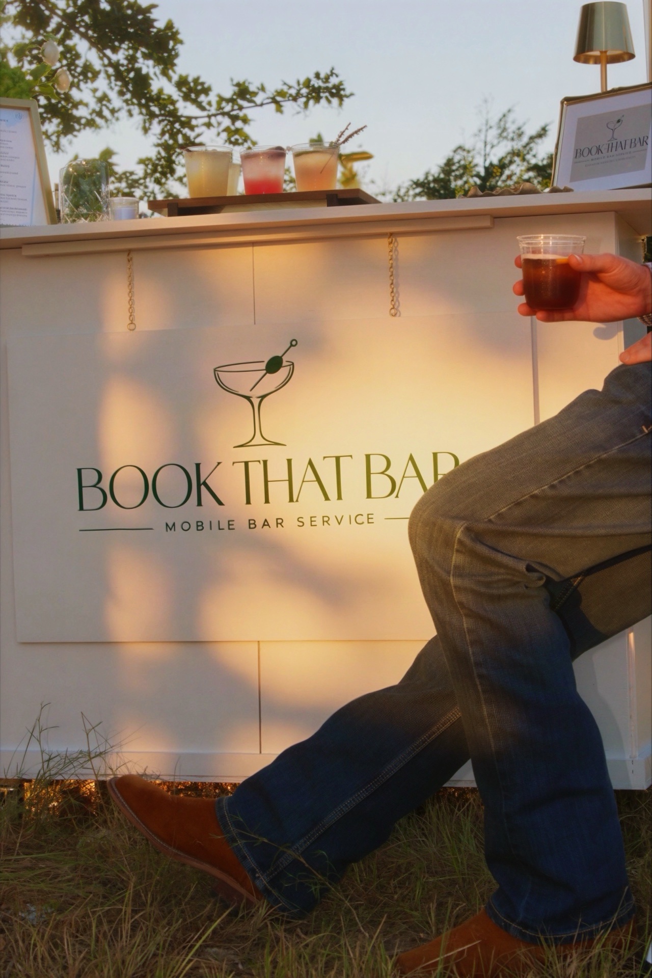 A guest enjoying a cocktail beside the Book That Bar mobile bar