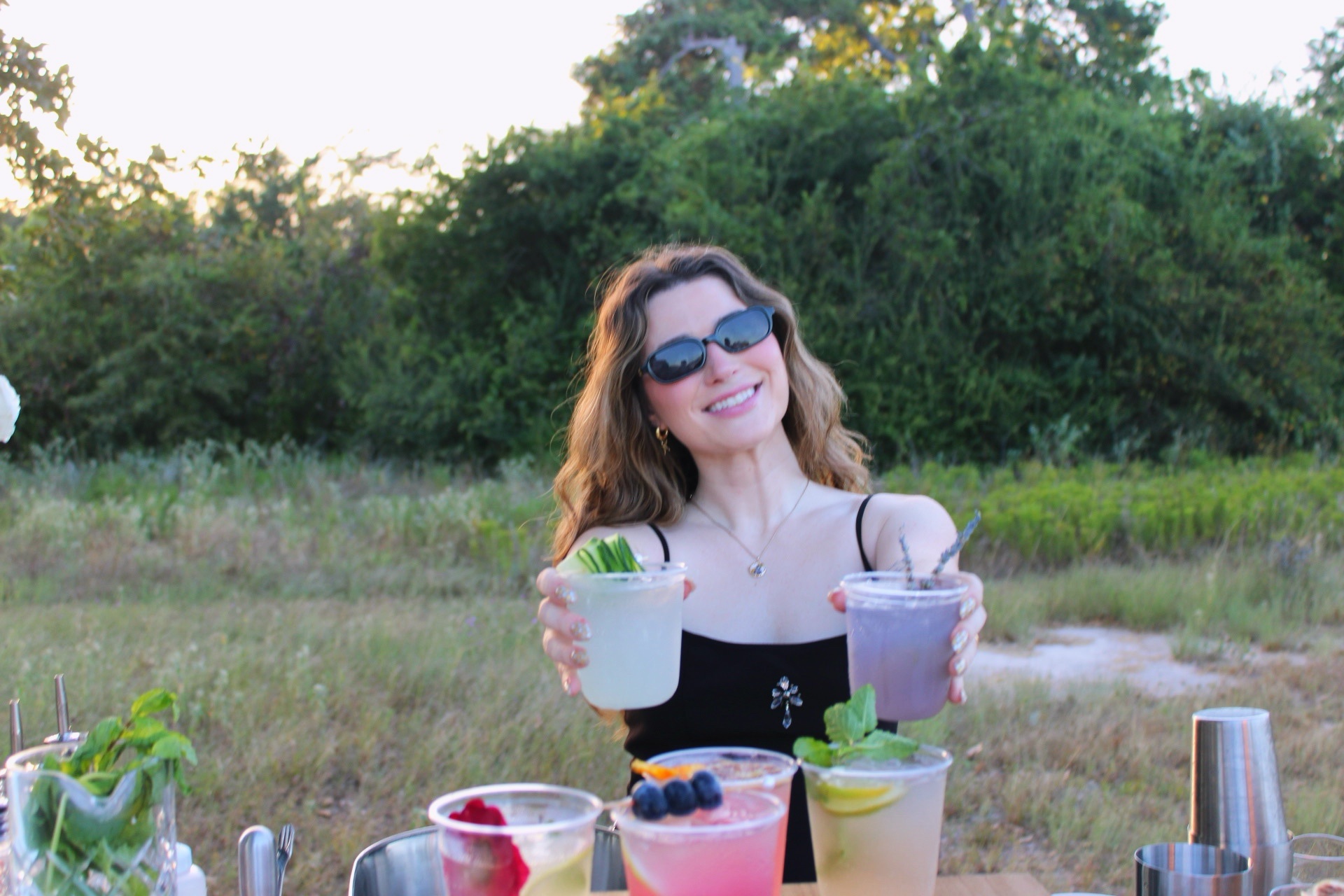Morgan smiling while holding two signature drinks