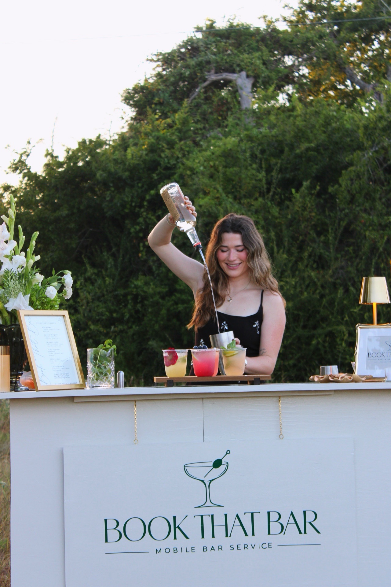 Morgan pouring a bottle behind the mobile bar