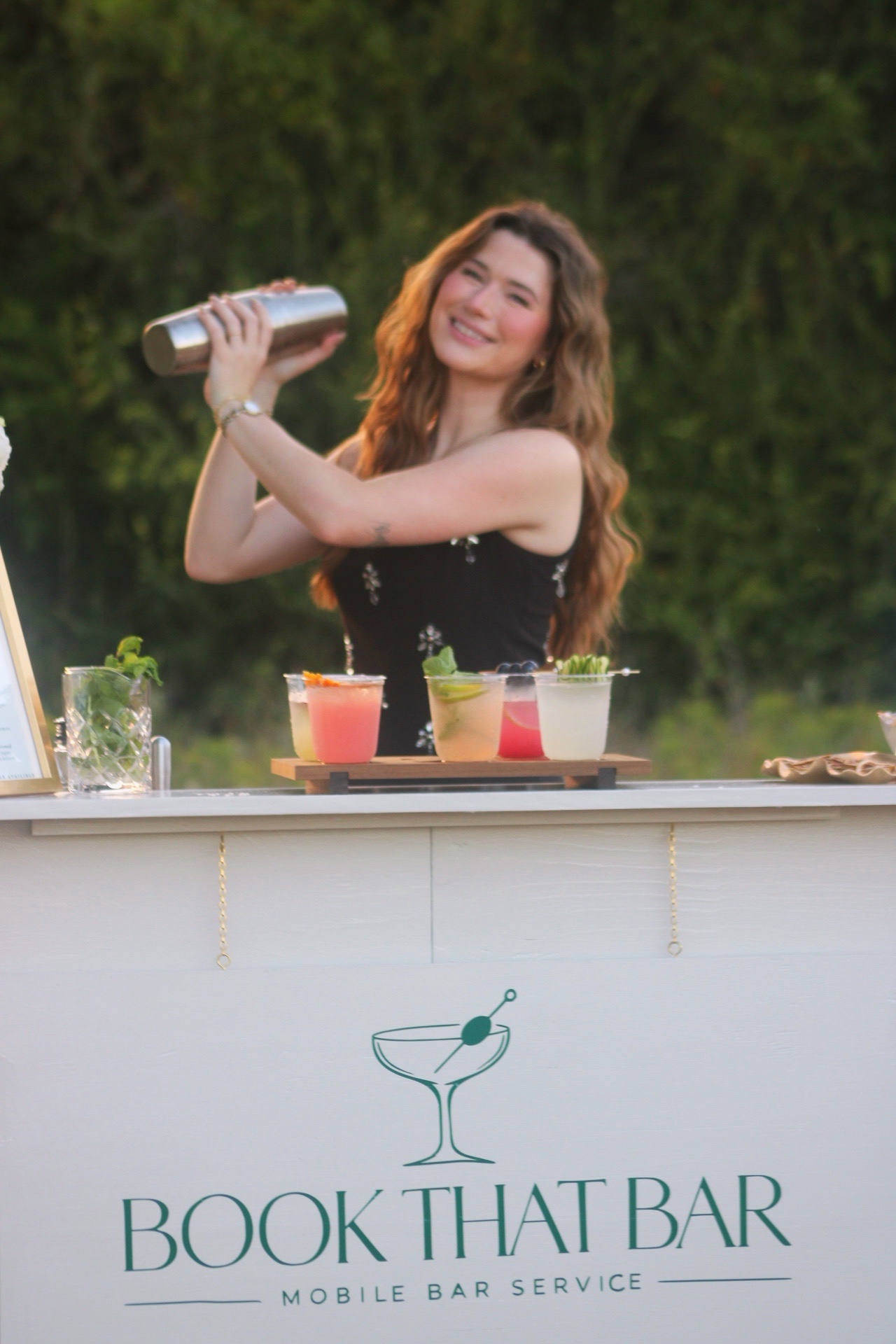 Morgan shaking a cocktail behind the Book That Bar mobile bar